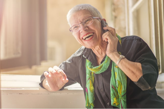 leende äldre kvinna pratar i mobiltelefon