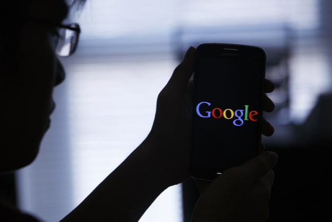 Person håller upp mobil med googles logga på skärmen.