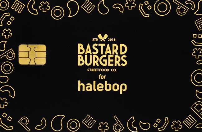 Ett svart kort med guldig text om samarbete mellan halebop och bastard burgers.
