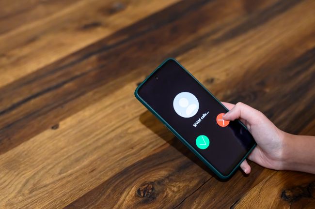 Hand håller mobil med samtal från okänd uppringare, koncept spoofing.