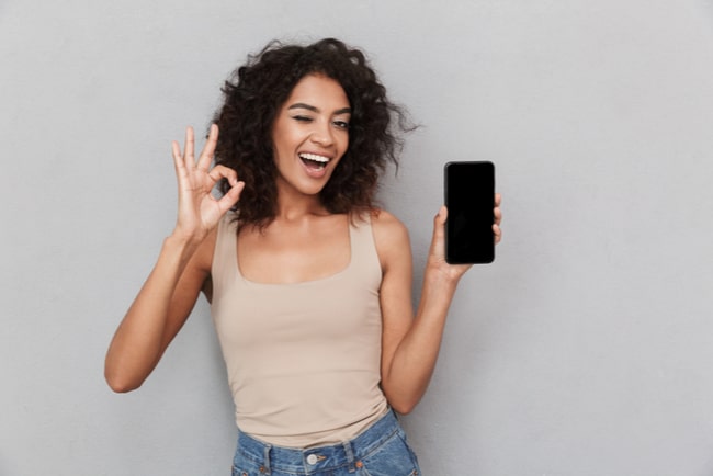 nöjd kvinna håller upp en smartphone