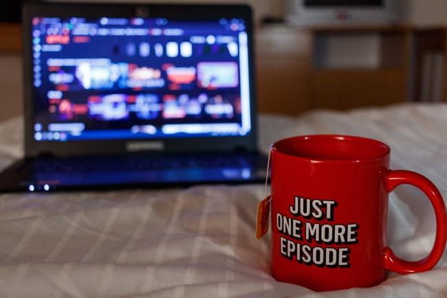 en temugg med text står på säng med laptop i bakgrunden